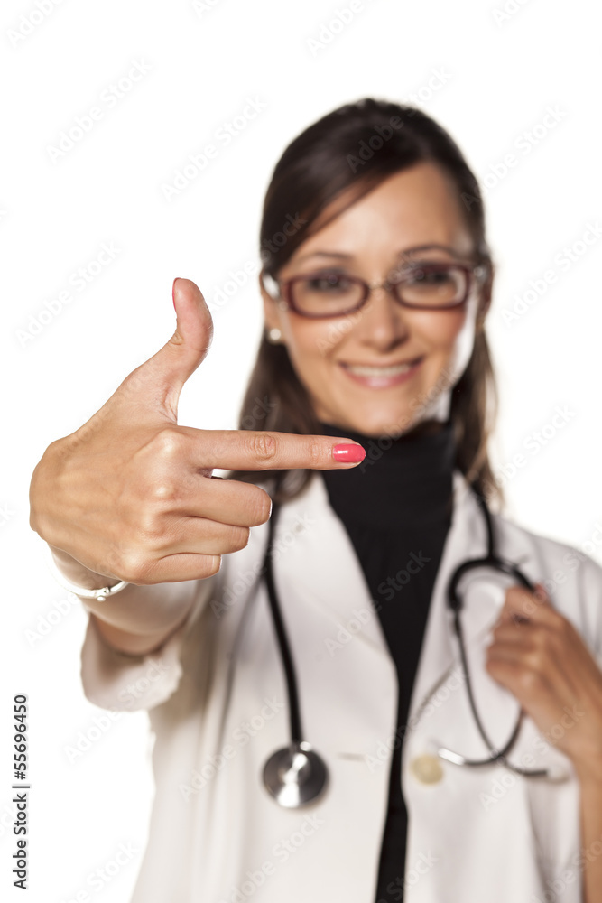 young and smiling woman doctor shows a direction with a finger