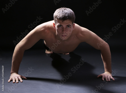 Handsome young muscular sportsman, on dark background