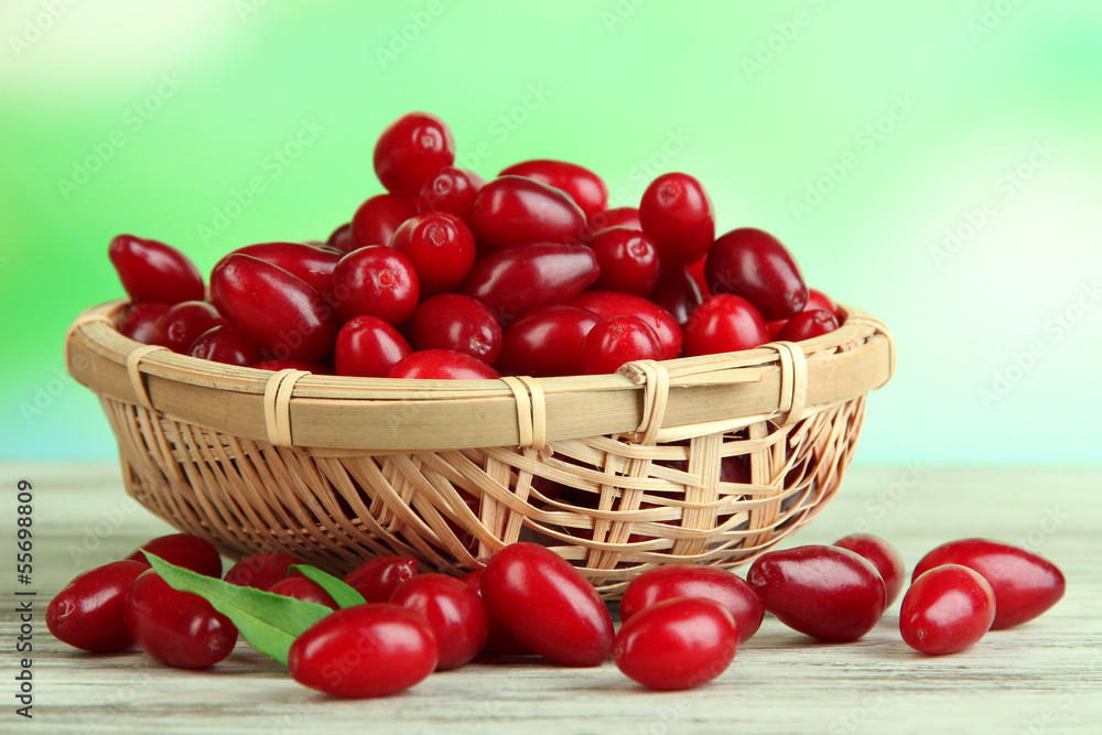 Fresh cornel berries in basket on wooden table Fresh cornel berries in basket on wooden table