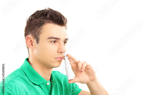 Young man spraying nose drops