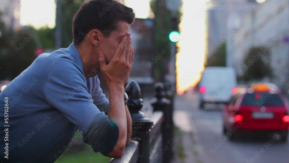 Headache depression by young male with moving traffic background