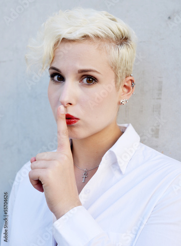 Beautiful blond woman holding a finger on her lips, silence please photo