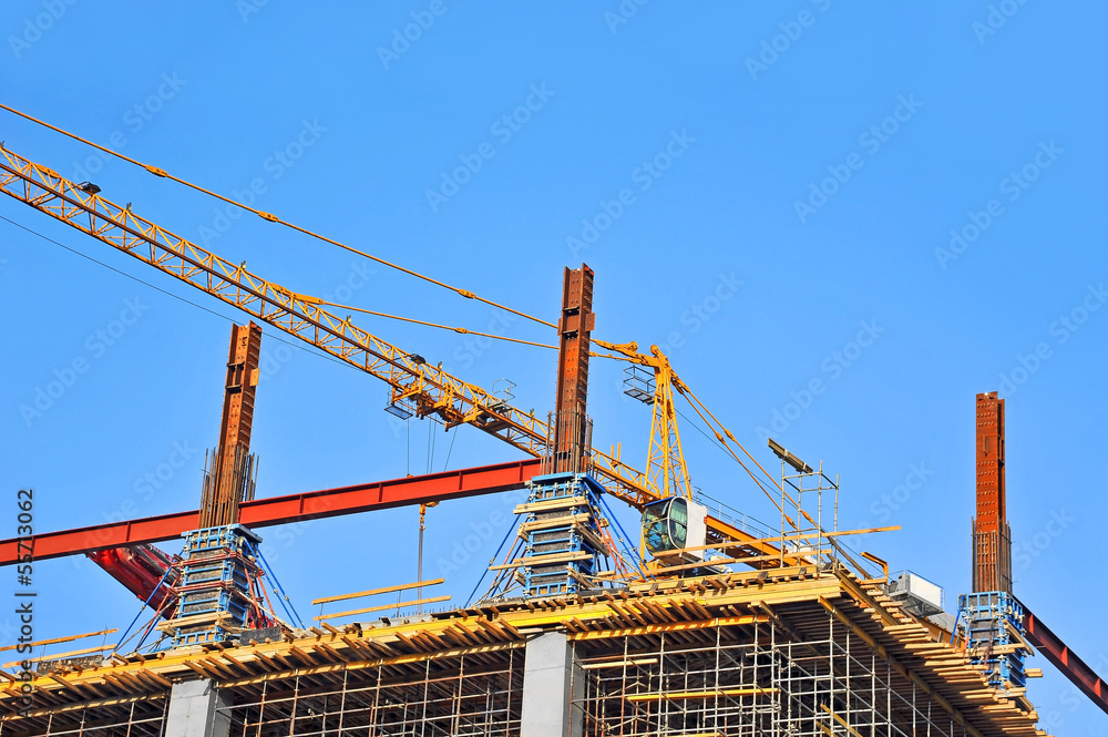 Crane and building construction site against blue sky Crane and building construction site against blue sky