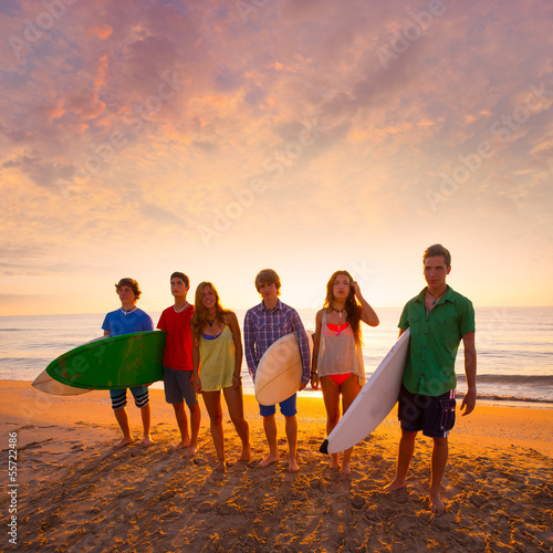 Surfers boys and girls group walking on beach