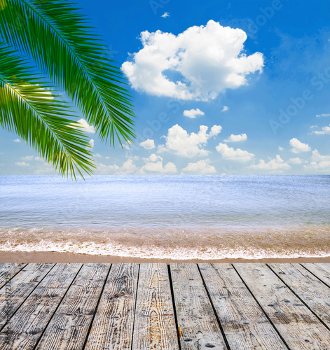 Tropical sea and beach with palm leaves and wooden floor