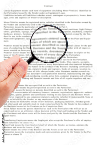 Hand holding magnifying glass reading document