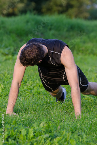 Handsome man doing push-ups at the park