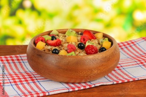 Oatmeal with fruits on table on bright background