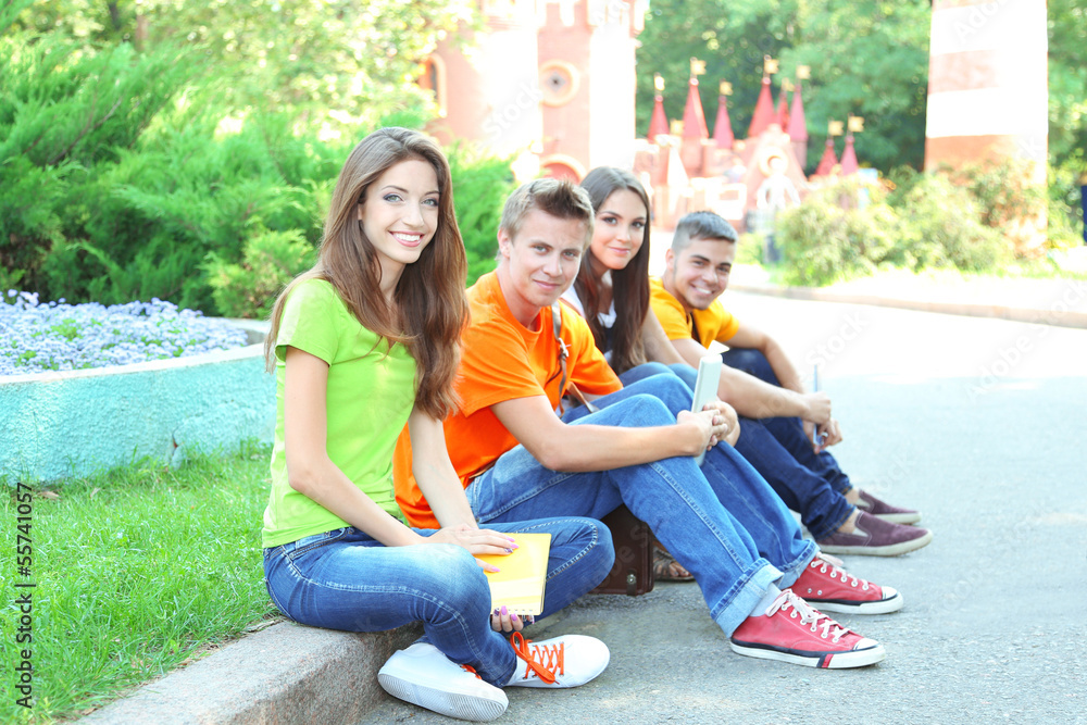 Happy group of young students sitting in park Happy group of young students sitting in park