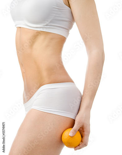 Slender female body holding orange on her leg. isolated 