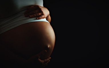 belly of pregnant woman  monochrome on dark background