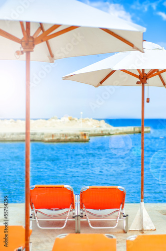 Beds and umbrellas on tropical beach with ocean background © aboutmomentsimages