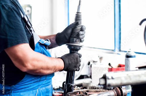 Auto car mechanic working on car shock absorber in car service