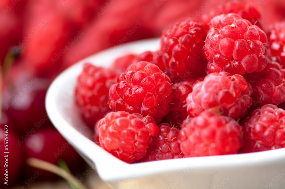 Organic and healthy raspberry in white bowl with wild berries on Organic and healthy raspberry in white bowl with wild berries on