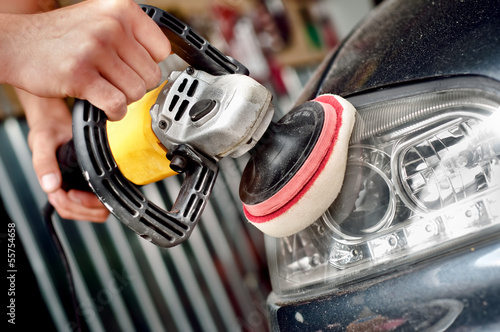 Car headlight cleaning with power buffer machine at car service
