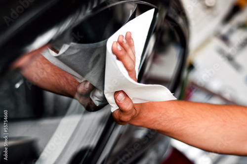 auto car worker and mechanic cleaning a cars window