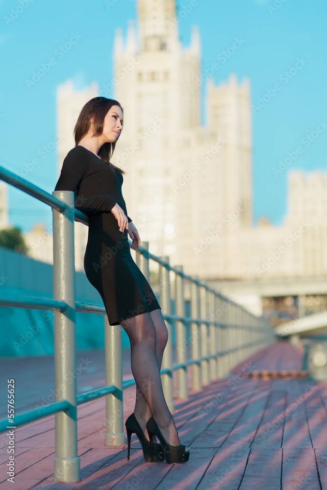 woman in black dress standing leaning on the railing