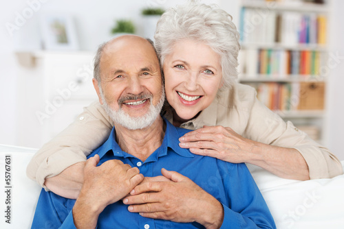 glückliches älteres paar umarmt sich auf dem sofa