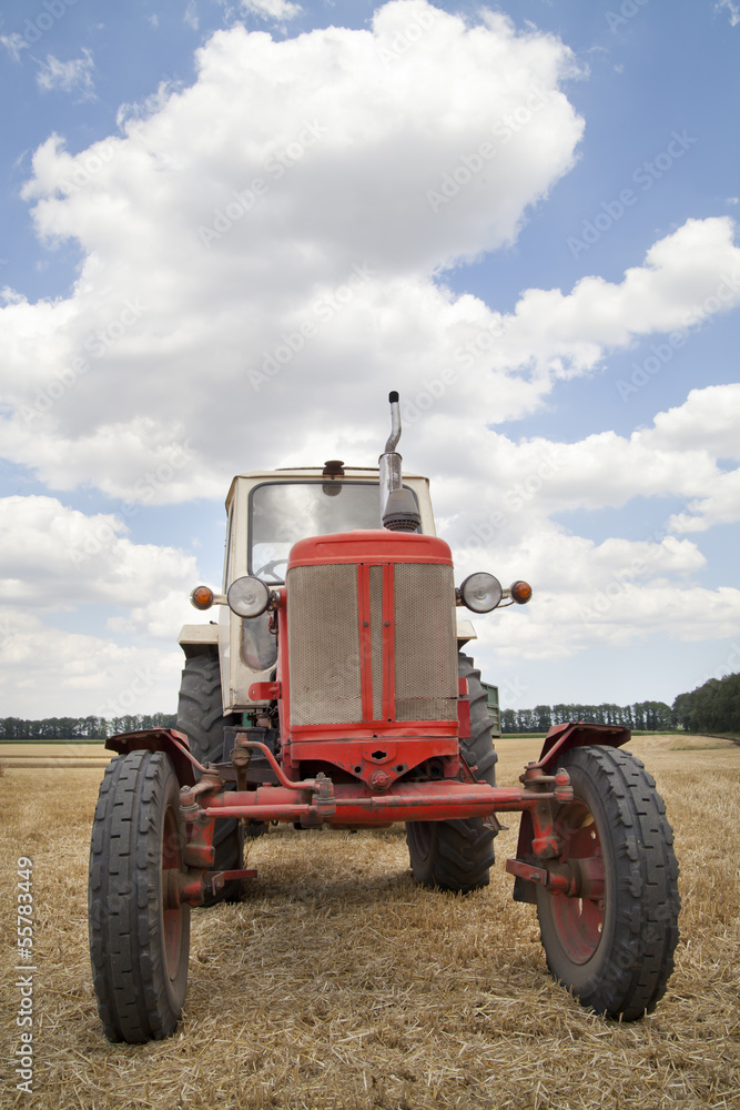 old tractor in field, against a cloudy sky old tractor in field, against a cloudy sky