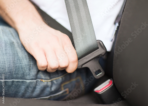 man fastening seat belt in car
