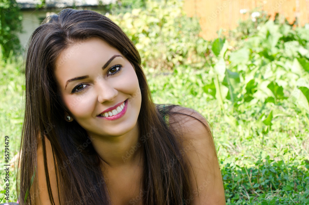 Girl smiling lying on the grass,relaxing in the garden in summer