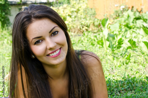 Girl smiling lying on the grass relaxing in the garden in summer