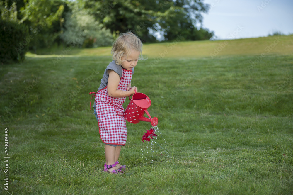 little girl with watering can in the garden