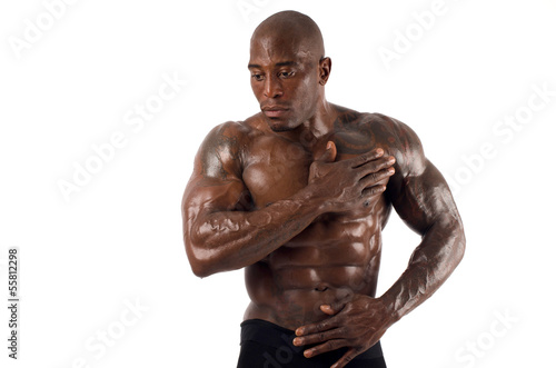 Black bodybuilder pouring oil on his muscles. Strong man