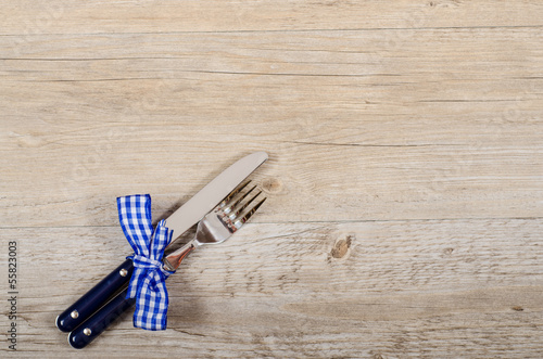 Blaue Messer und Gabel mit karierter Schleife auf einem Tisch