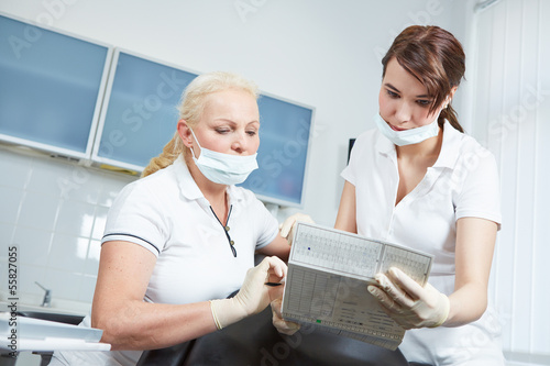 Dentist and dental assistant reading medical records