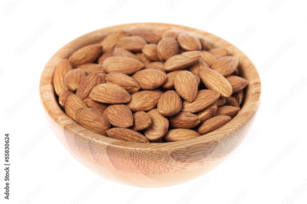 Almonds in a brown wooden bowl isolated on white background Almonds in a brown wooden bowl isolated on white background