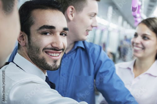 Portrait of young smiling businessman standing on the subway  looking at camera 