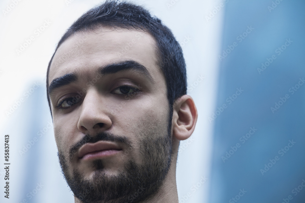 Fototapeta premium Portrait of serious young businessman, outdoors, business district, close-up