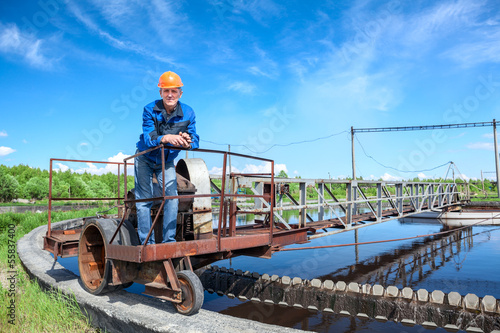 Senior worker standing on waste water treatment unit on plant
