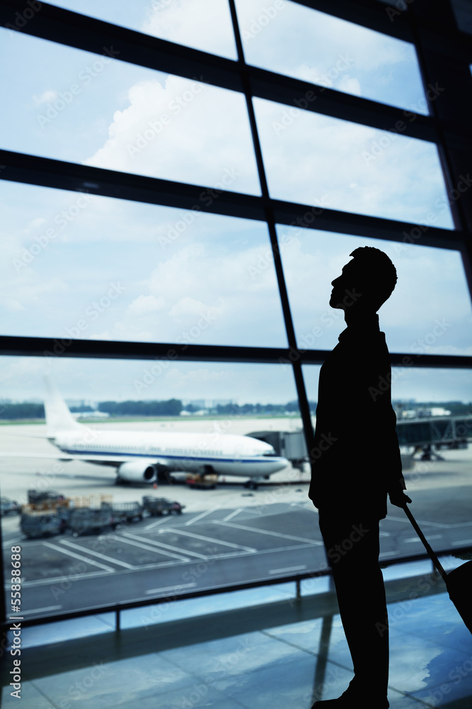 Silhouette of businessman waiting in the airport and looking out the window Silhouette of businessman waiting in the airport and looking out the window