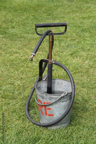 A Vintage Stirrup Pump in a Metal Fire Bucket.