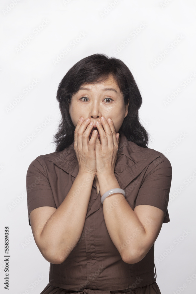 Portrait of shocked and surprised woman with hands covering her mouth, studio shot Portrait of shocked and surprised woman with hands covering her mouth, studio shot