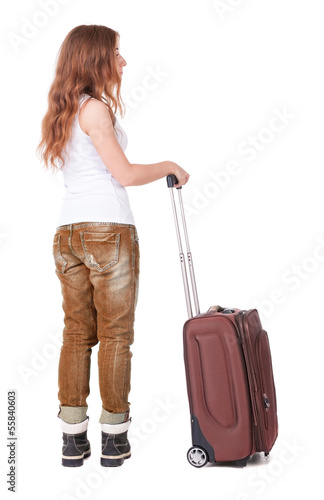 Back view of stylishly dressed woman with suitcase looking up