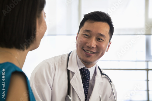 Photography Smiling doctor sitting down and consulting patient in the hospital, close-up