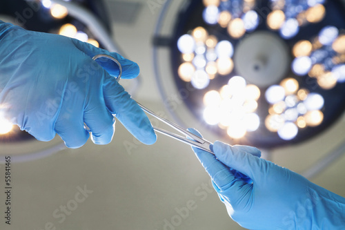 Fotografie, Obraz Close-up of gloved hands passing the surgical scissors, operating room, hospital