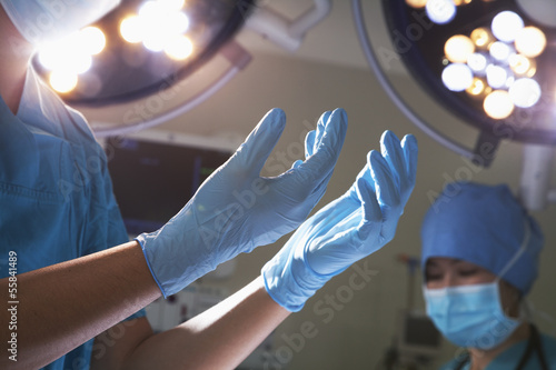 Midsection view of hands in surgical gloves and surgical lights in the operating room  photo