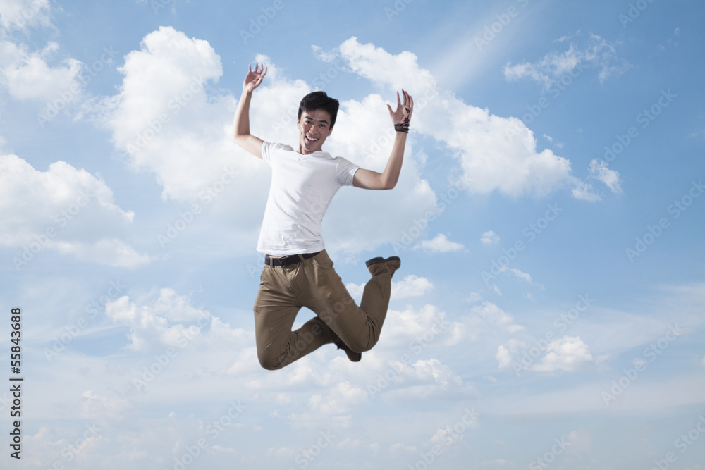 Young smiling man jumping in mid-air, sky and cloud background Young smiling man jumping in mid-air, sky and cloud background