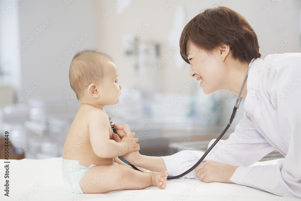 Doctor checking baby's heart beat with a stethoscope in the doctors office Doctor checking baby's heart beat with a stethoscope in the doctors office
