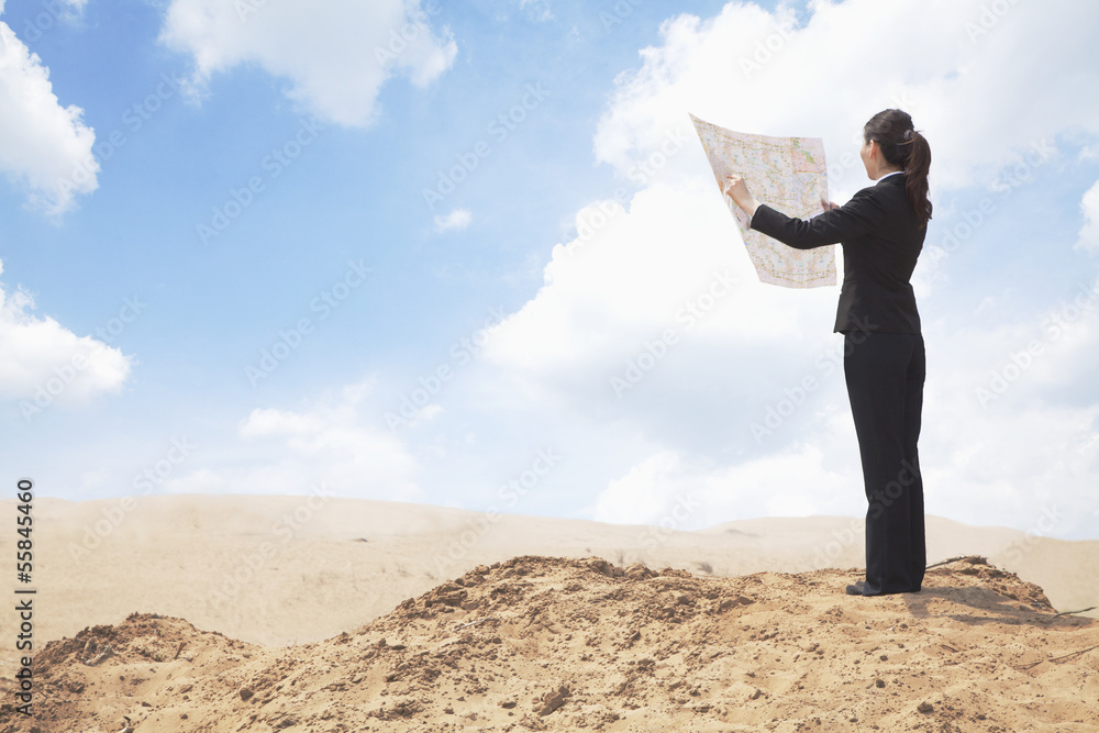 Young Businesswoman looking at a map in the middle of the desert 