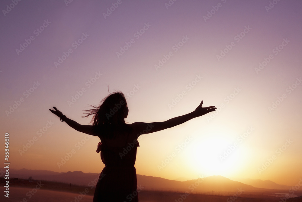Serene young woman with arms outstretched doing yoga in the desert in China, Silhouette