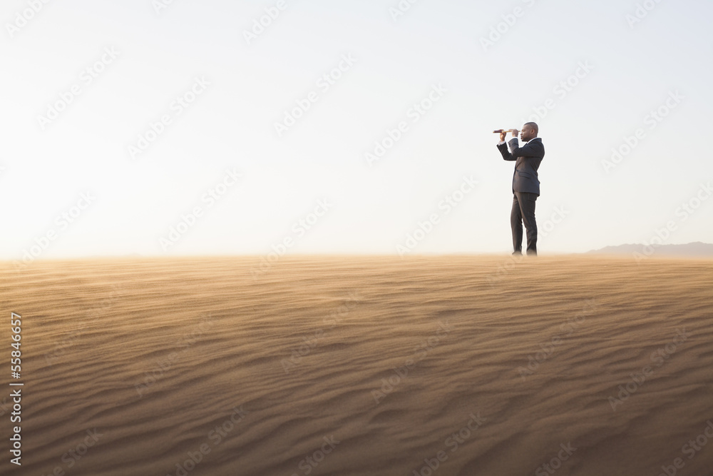 Young businessman looking through telescope in the middle of the desert Young businessman looking through telescope in the middle of the desert