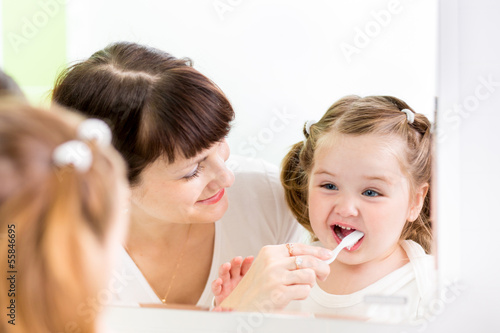 mother kid brushing kid teeth