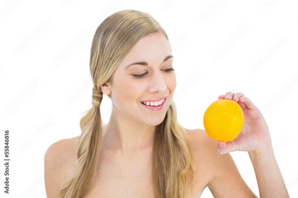 Pleased young blonde woman looking at an orange Pleased young blonde woman looking at an orange