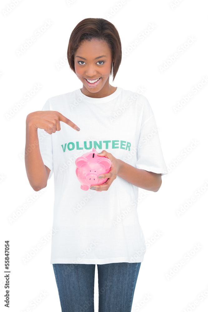 Smiling woman pointing at her piggy bank Smiling woman pointing at her piggy bank