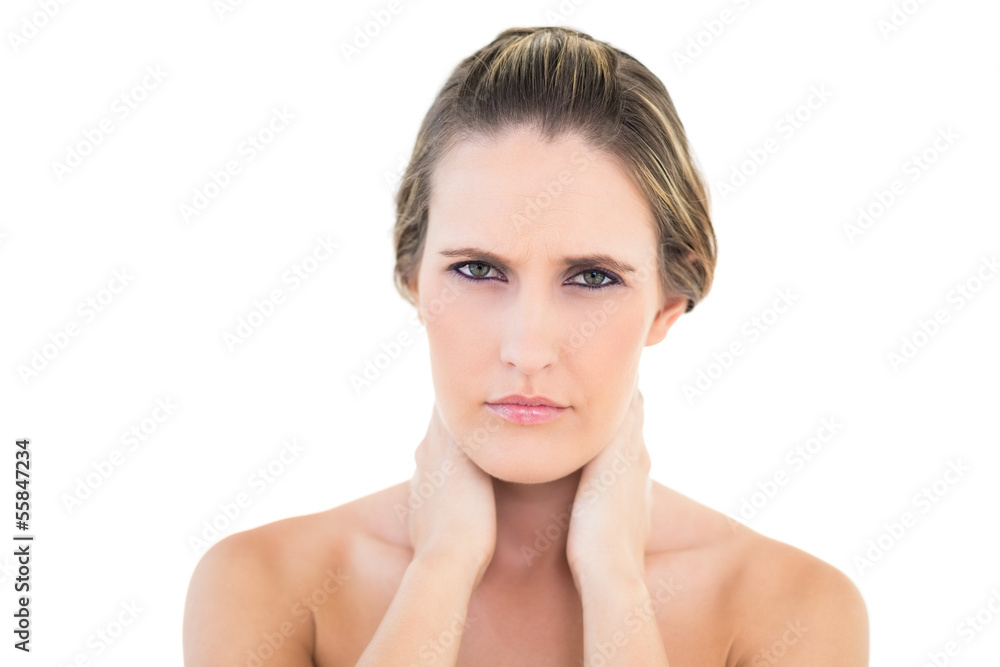 Disgruntled woman looking at camera with a sore neck Disgruntled woman looking at camera with a sore neck